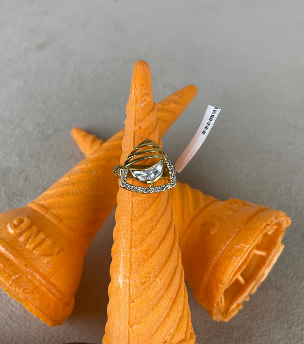 A gold and silver ring with a clear central gemstone and small clear stones along the band, displayed on an orange 3D-printed cone-shaped stand against a gray background.