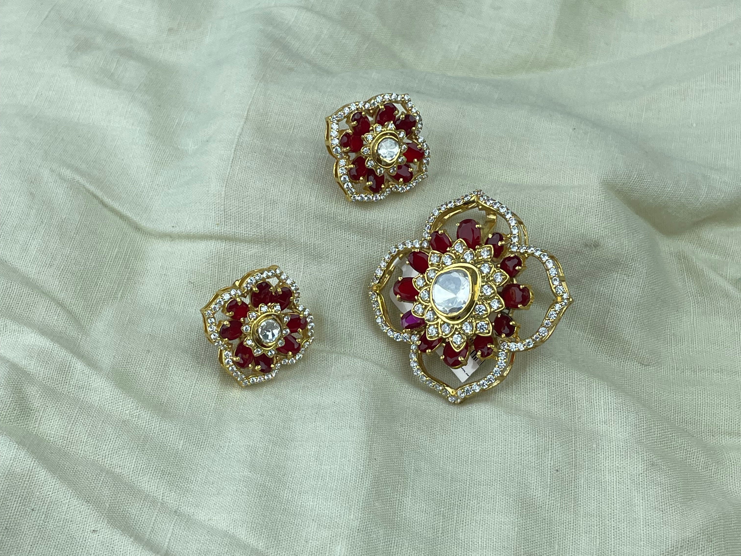 Raktima Pendant Set with deep red stones, clear polki accents, and gold-toned floral detailing.
