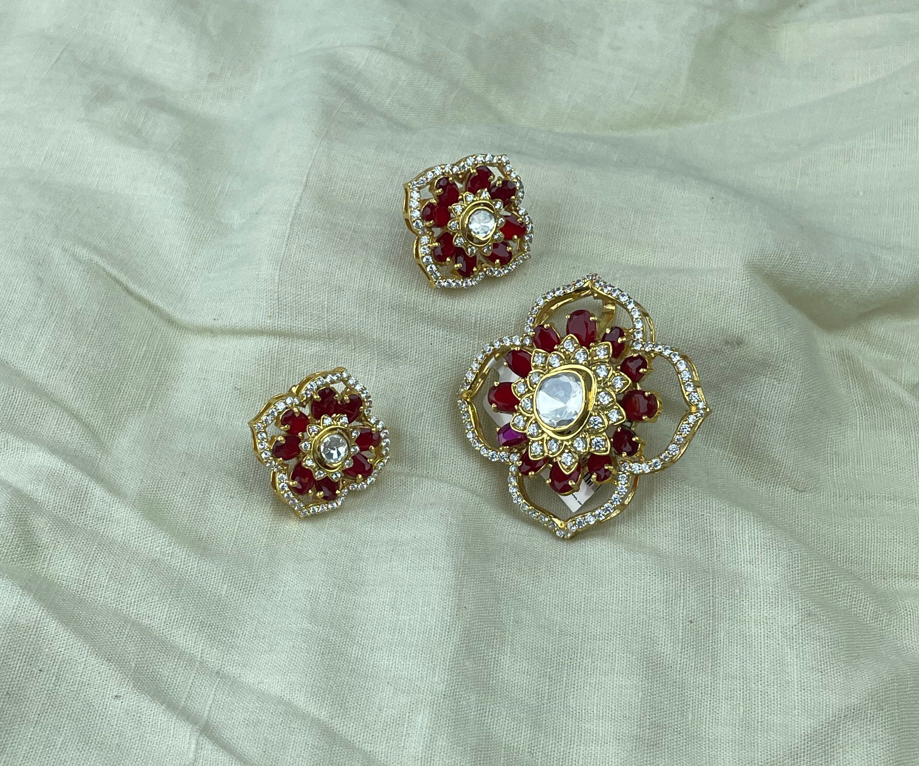 Raktima Pendant Set with deep red stones, clear polki accents, and gold-toned floral detailing.
