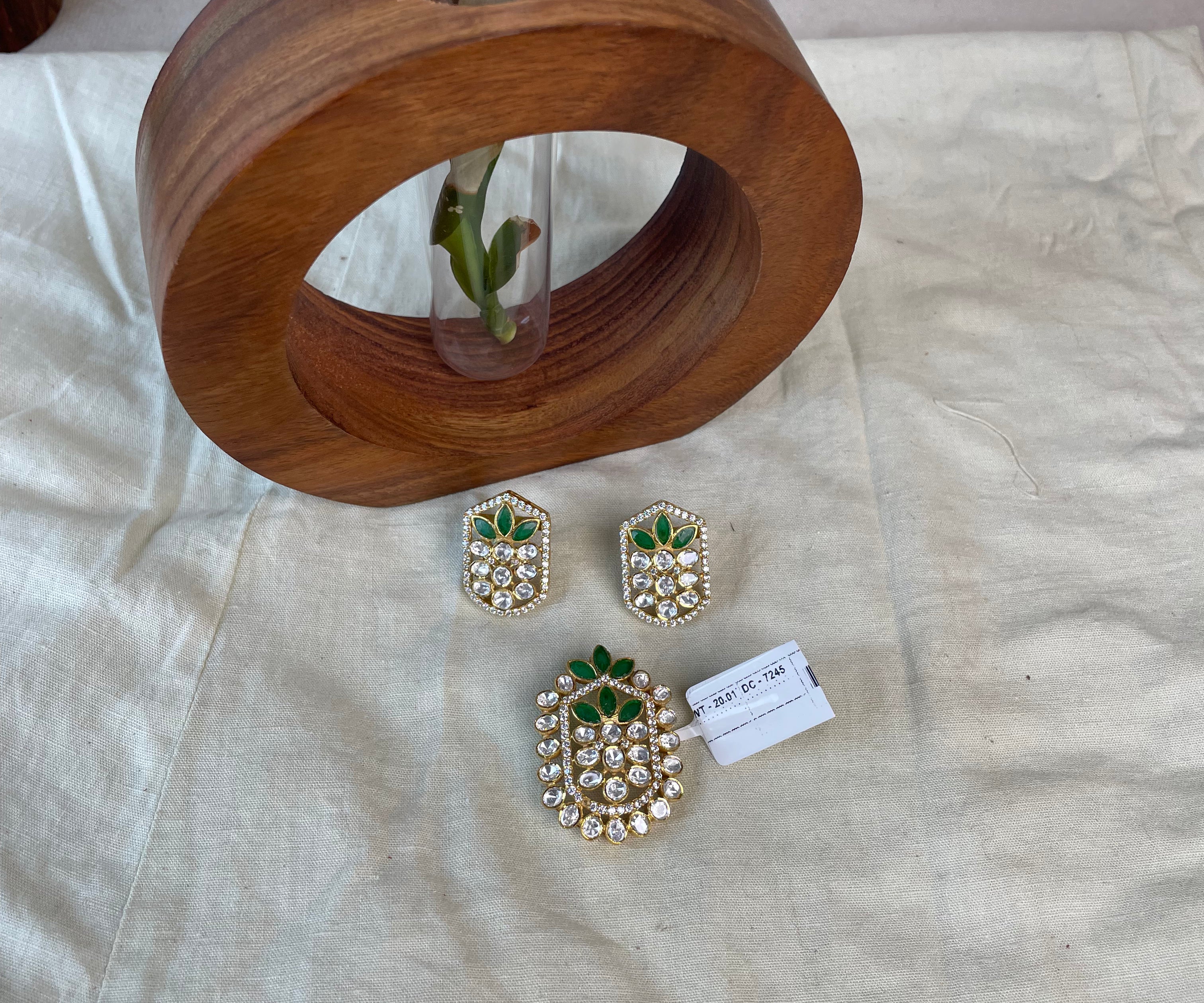 Pallavika jewellery set featuring green petal-shaped stones and sparkling clear stone accents.
