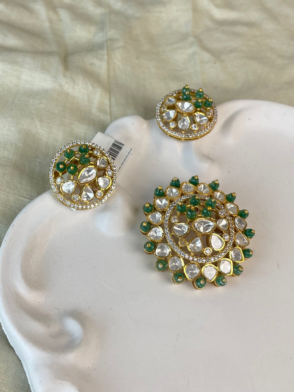 Mayurika Pendant Set with a round layered gold-toned pendant and matching earrings, clear stones, and green bead accents.